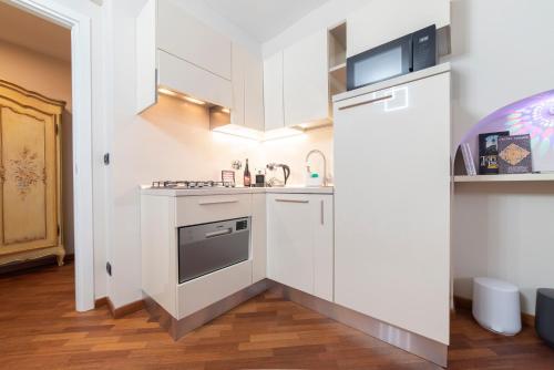 una pequeña cocina con armarios blancos y fregadero en TO-Housing2 en Turín