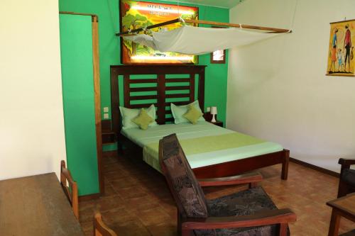 a bedroom with a bed with a green wall at Hotel De La Baie in Diego Suarez