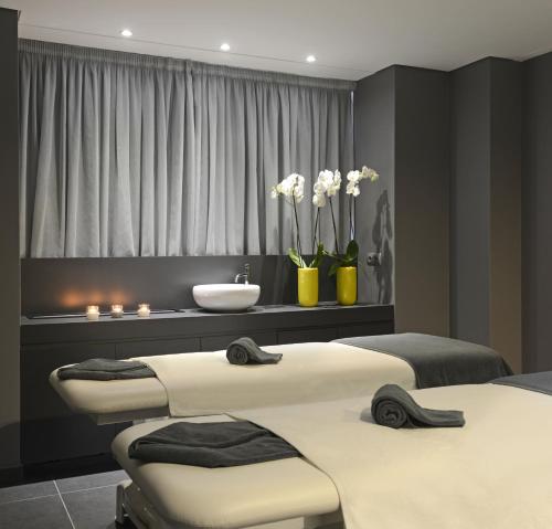 two beds in a room with a sink and a bathroom at Altis Grand Hotel in Lisbon