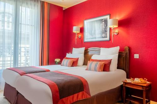 a bedroom with a large bed with red walls at Hotel Trianon Rive Gauche in Paris