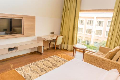 a hotel room with a bed and a desk and a window at Tivoli Garden Resort in New Delhi