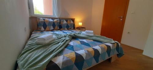 a bed with a blanket on it in a room at Apartman Kos in Zamet