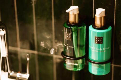 two green bottles of soap sitting next to a mirror at Hotel Septembar in Podgorica