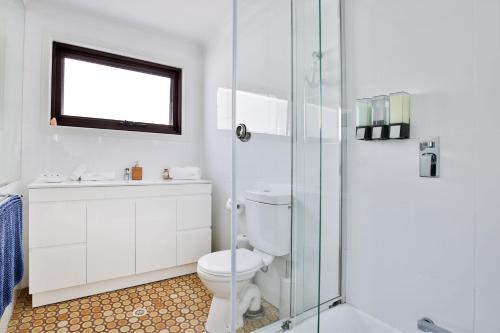 a bathroom with a toilet and a glass shower at Azure Absolute Beachfront I Pet Friendly in Callala Beach