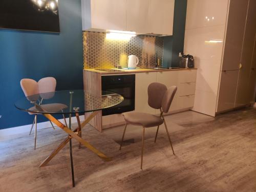 a kitchen with a glass table and chairs in a room at Piotrkowska.eu Apartament Romantica in Łódź
