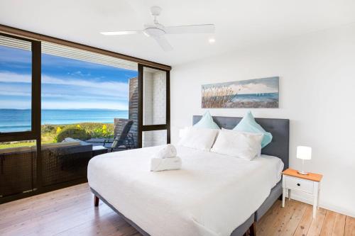 Callala BeachにあるAzure Absolute Beachfront I Pet Friendlyの海の景色を望むベッドルーム1室(大型ベッド1台付)