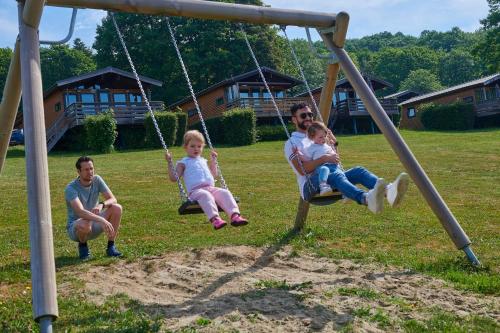 a man and two children sitting on a swing at Vallée Les Etoiles in Blaimont
