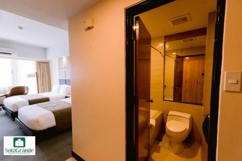 a hotel room with a bathroom with a toilet and a bed at Sotogrande Hotel and Resort in Mactan