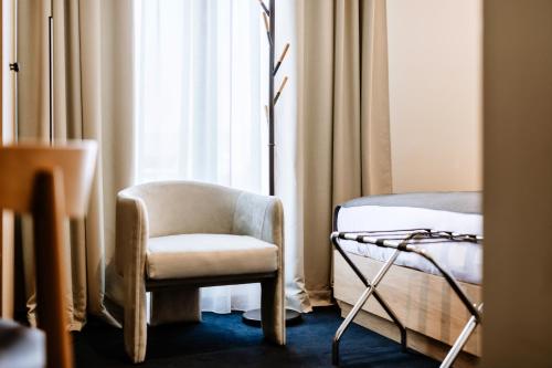 a room with a chair and a bed and a window at Hotel Septembar in Podgorica