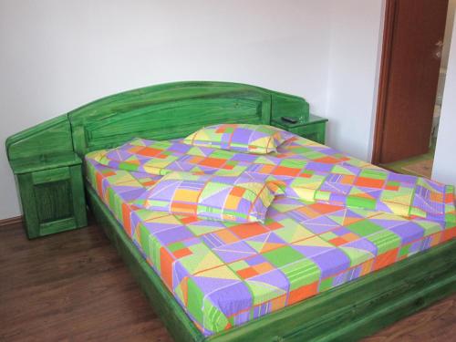 a green bed with a colorful comforter in a bedroom at Casa Felicia in Moieciu de Jos