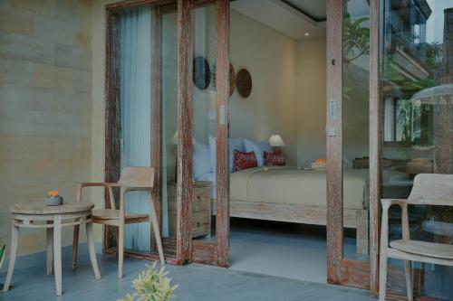a bedroom with a bed and a table and chairs at LASTANA SUITE UBUD in Ubud