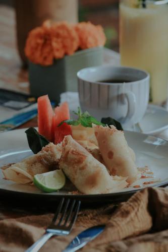 a plate of food with fish and a cup of coffee at LASTANA SUITE UBUD in Ubud