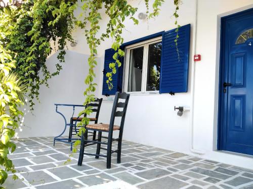 a patio with two chairs and a blue door at Nissos Ios in Mylopotas