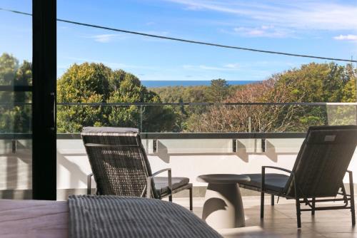a balcony with two chairs and a table and a view at Grandview Villa Kingscliff - Oceanview Tri-level Villa by uHoliday in Kingscliff