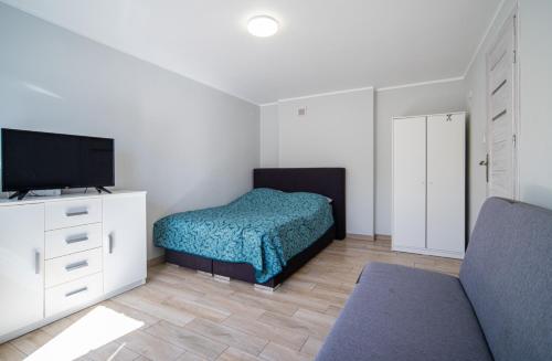 a bedroom with a bed and a flat screen tv at Pensjonat Basia in Dziwnówek
