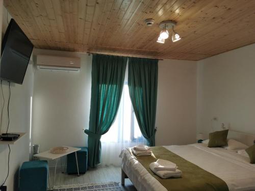 a bedroom with a bed and a window with green curtains at Pensiunea Delta Blue in Maliuc