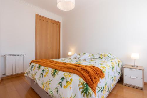 a white bedroom with a bed with a orange blanket at Foz Village Beach by Rent4All in Buarcos