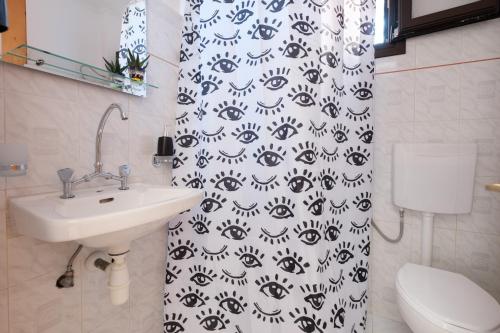 a bathroom with a sink and a black and white shower curtain at Mouzakitis Apartments 4 in Arillas