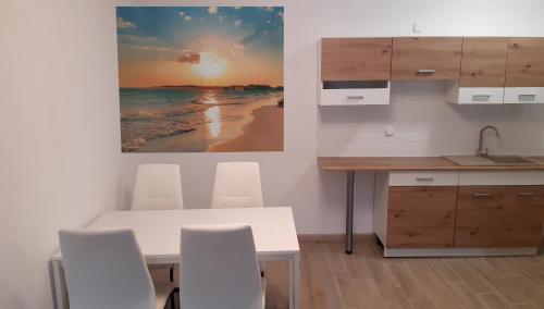 a kitchen with a table and chairs and a picture of the beach at Apartamenty Słoneczne Tarasy in Mrzeżyno