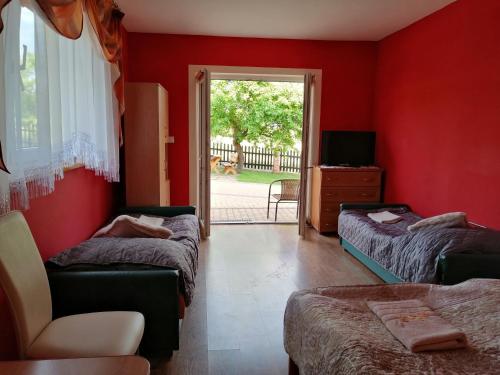 a red room with two beds and a chair at Rzepedka in Rzepedż