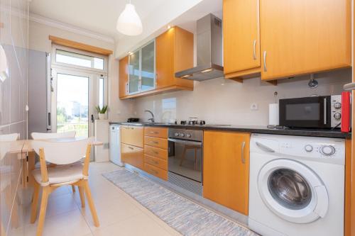 a kitchen with a washing machine and a table at Foz Village Beach by Rent4All in Buarcos