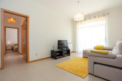 a living room with a couch and a tv at Foz Village Beach by Rent4All in Buarcos