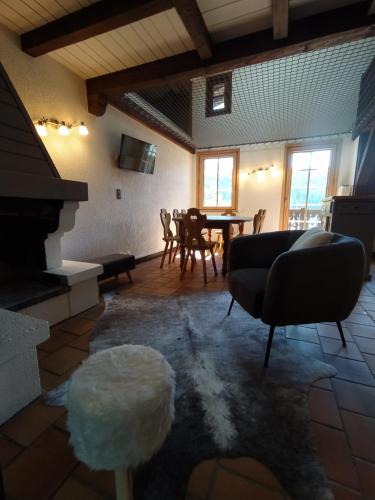a living room with a couch and a table with chairs at Chalet Appart'Hôtel l'Eau Vive in Saint-Nicolas-la-Chapelle