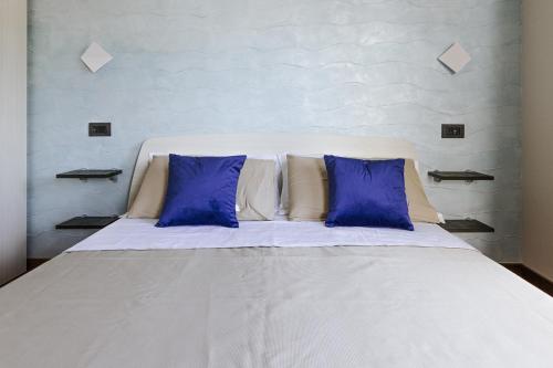 Elle comprend un grand lit blanc avec des oreillers bleus. dans l'établissement APULIA BLUE APARTEMENTS & B&B, à Bari