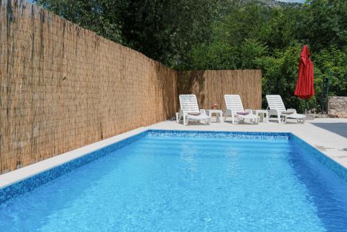 una piscina con 2 sillas y una sombrilla roja en Villa Old Town Stolac, en Stolac