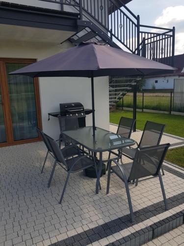 a picnic table and chairs under an umbrella at Apartamenty Tylicki Poranek in Tylicz