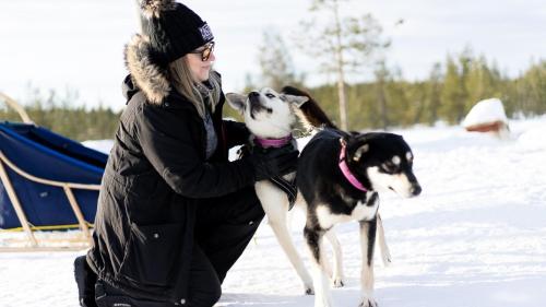 a woman standing in the snow with a dog at Heteranta, Lake Inari / Inarijärvi in Inari