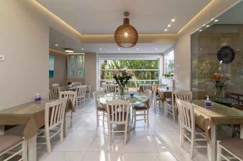 a dining room with tables and chairs and a large window at Troulis Seaside in Amoudara Herakliou