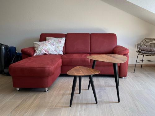 a red couch in a living room with two tables at Weingut & Straußwirtschaft Vogel in Vogtsburg