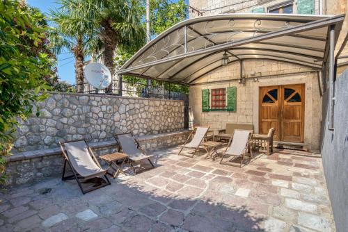um pátio com cadeiras e mesas e uma parede de pedra em Stone Home Kotor em Dobrota