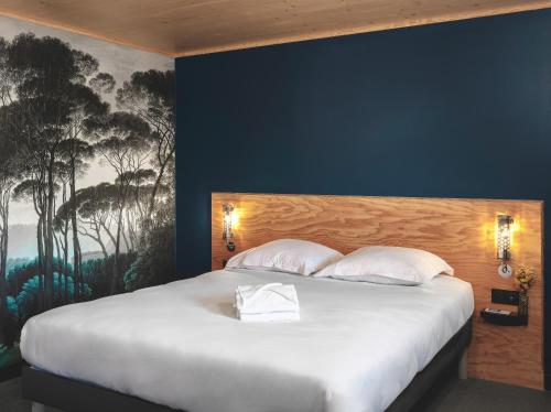 a bedroom with a large white bed with a painting on the wall at Eklo Toulouse in Toulouse