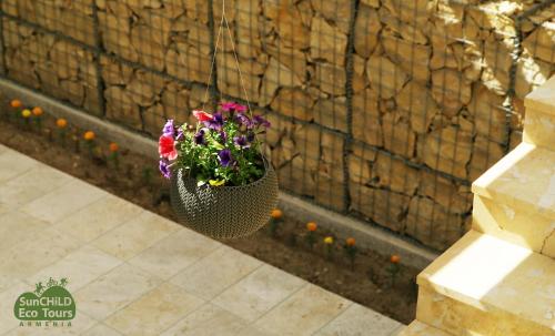 a pot of flowers hanging from a wall at Gnishik Eco Lodge in Gnishik
