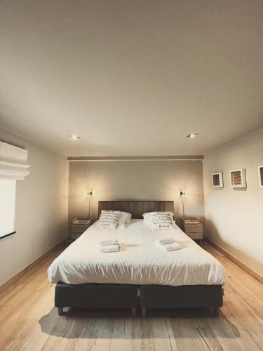 a bedroom with a large white bed with two lamps at Domaine Sur Les Sarts in Ohey