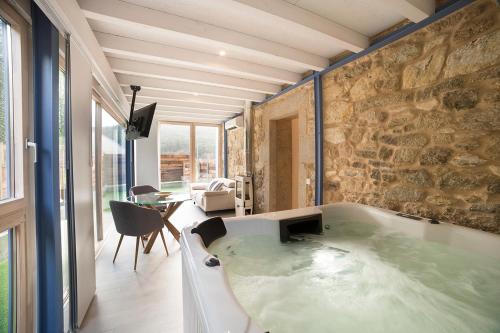 a large bath tub in a room with a stone wall at Luz de Viro in Outes