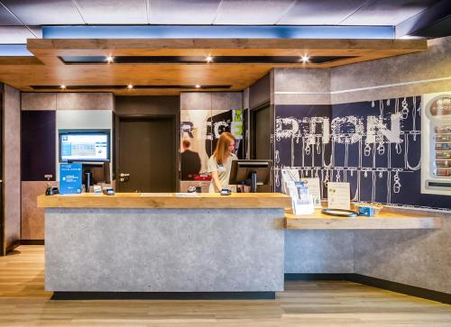 a woman standing at a counter in a restaurant at ibis Budget Courbevoie Paris La Défense in Courbevoie