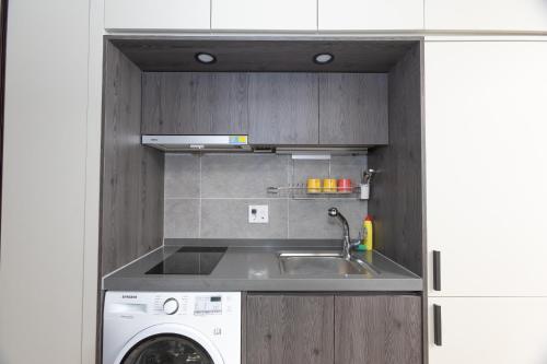 a kitchen with a sink and a washing machine at Golden Planet Hotel in Icheon
