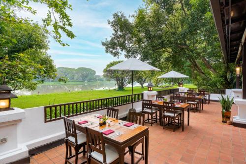 a patio with tables and chairs and a view of a river at The Legend Chiang Rai Boutique River Resort & Spa in Chiang Rai