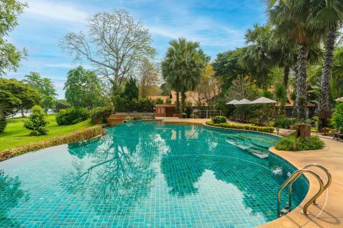 a swimming pool in a yard with trees at The Legend Chiang Rai Boutique River Resort & Spa in Chiang Rai