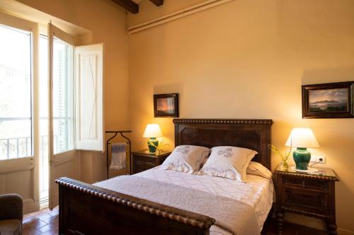 1 dormitorio con 1 cama con 2 mesitas de noche y 2 lámparas en Masia Can Comas, en Sant Pere de Riudebitlles