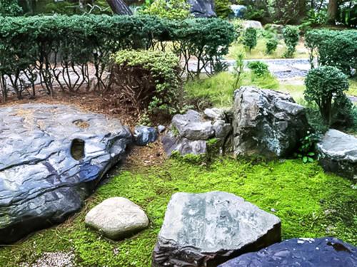 a garden with large rocks and green grass at Ryokan Karasawa in Kanazawa