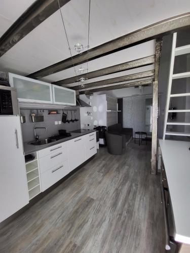 a kitchen with white cabinets and a living room at Studio mezzanine Saint Bres. 20min de Montpellier in Saint-Brès