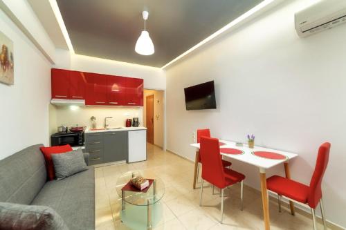a living room and kitchen with a table and red chairs at Blue Boutique Apts in Amoudara Herakliou
