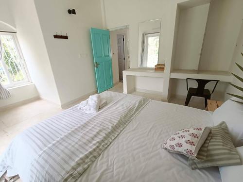 a bedroom with a large white bed with a blue door at Beseco Bed and Breakfast in Benaulim