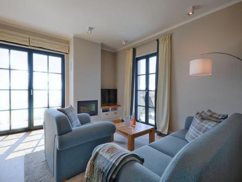 un soggiorno con due divani blu e una TV di Reetland am Meer - Premium Reetdachvilla mit 3 Schlafzimmern, Sauna und Kamin F23 a Dranske