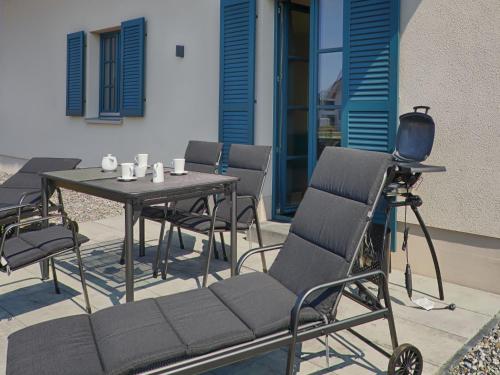 un tavolo e sedie su un patio con macchina fotografica di Reetland am Meer - Premium Reetdachvilla mit 3 Schlafzimmern, Sauna und Kamin F23 a Dranske