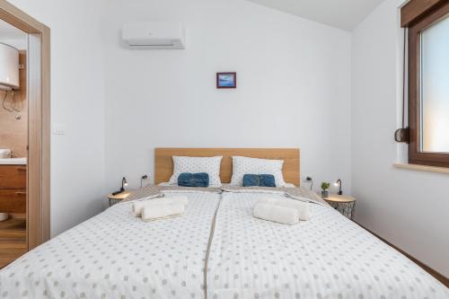 a white bedroom with a large bed with blue pillows at Rental house Nada in Fažana